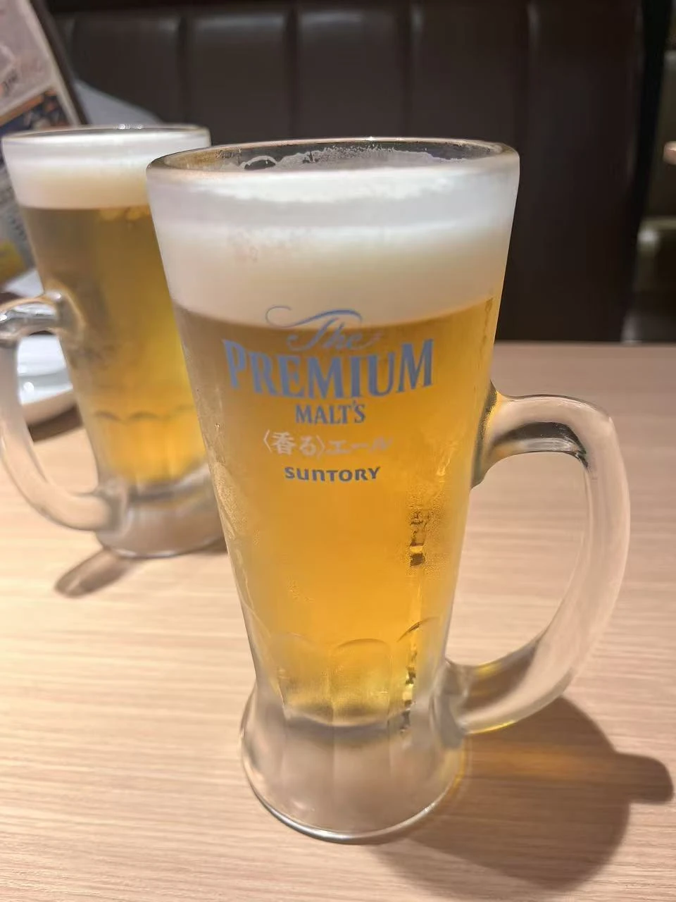 木桌上带着泡沫与冷凝水的啤酒杯