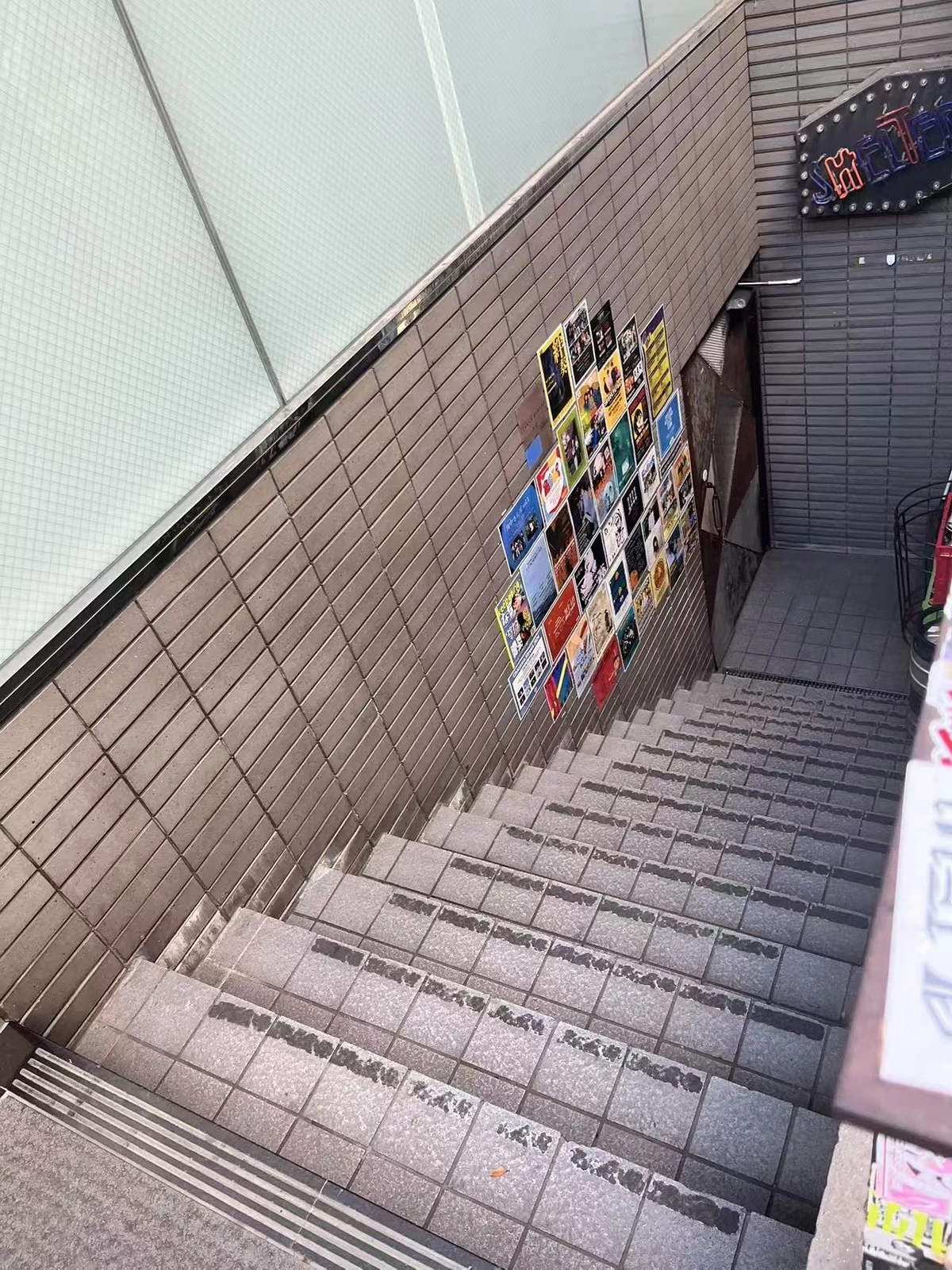 从街边向下延伸至 SHELTER 入口的砖墙阶梯与海报