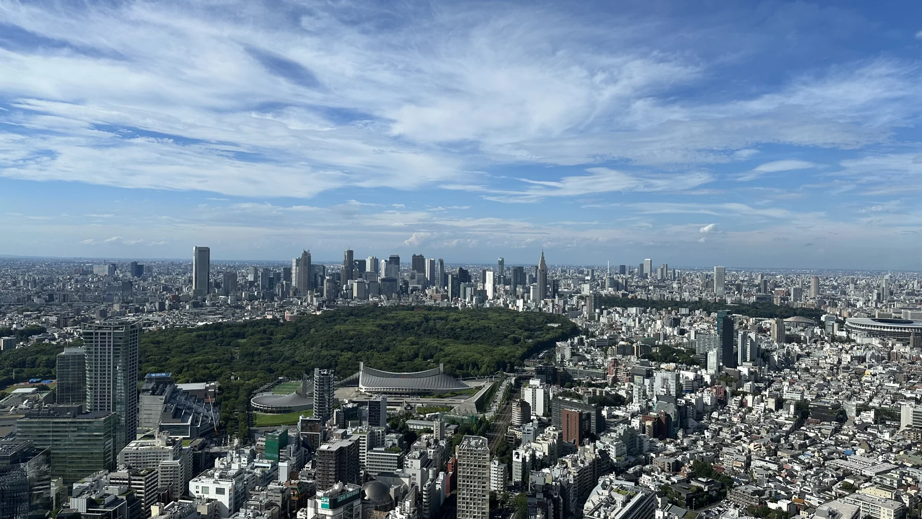蓝天与舒展的云层下,大片绿地被城市建筑环绕