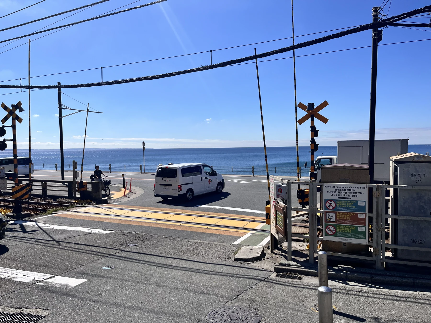 蓝天海面前的铁路道口与经过的白色车辆