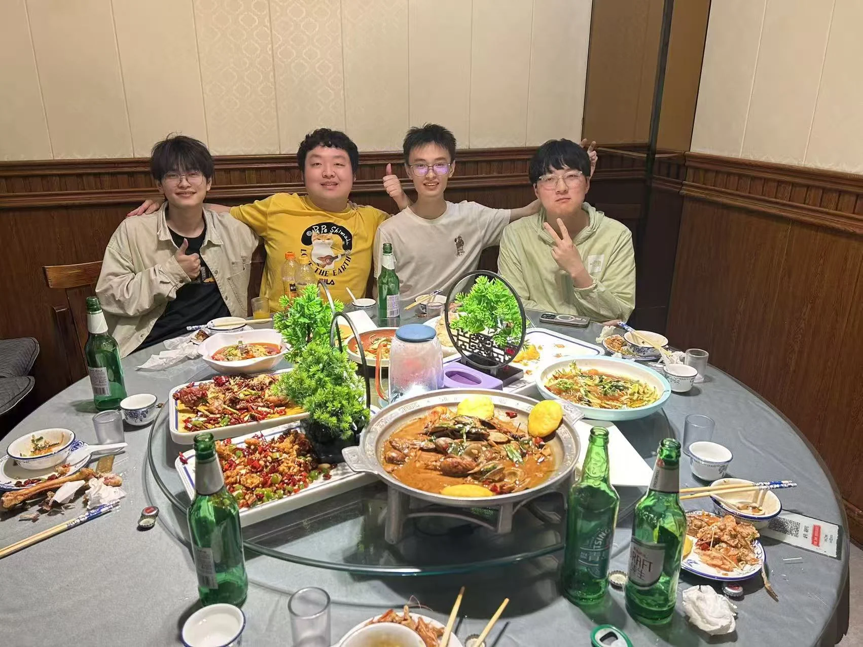 四位大学室友围坐在摆满菜的圆桌旁合影