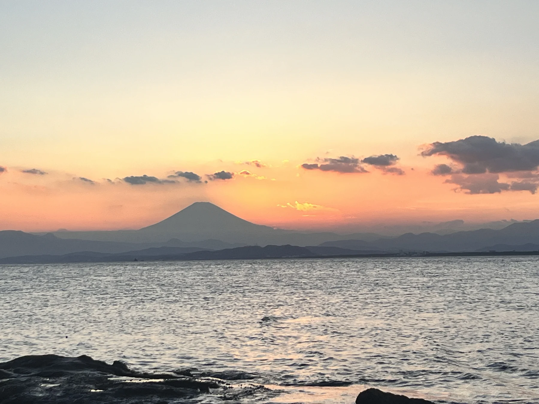 夕阳下的海面、云朵与远山